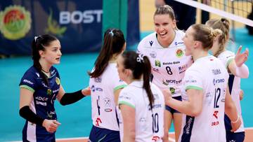 Grupa siatkarek w białych strojach sportowych cieszy się po wygranym meczu.