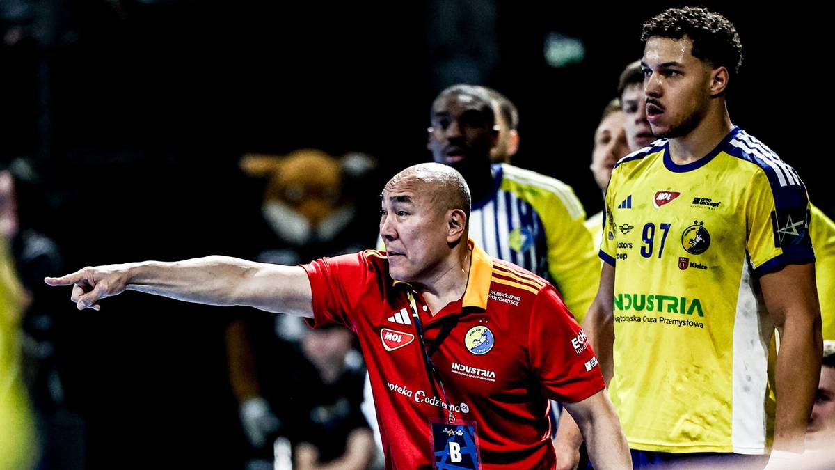 Trener w czerwonej koszulce gestykuluje, wskazując palcem w bok, otoczony przez zawodnik&oacute;w w ż&oacute;łtych strojach sportowych.