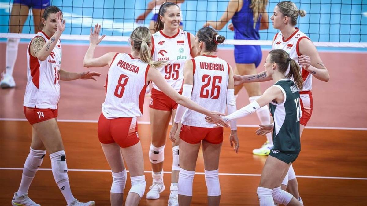 Grupa zawodniczek siatk&oacute;wki w białych strojach, świętujących na boisku.