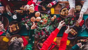 Ludzie siedzący przy świątecznym stole podczas posiłku, jedzący i pijący.