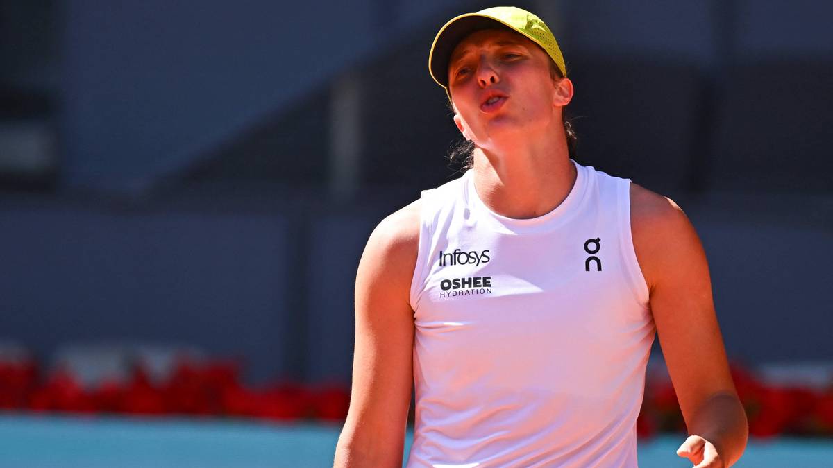 Iga Świątek, polska tenisistka, w białej koszulce bez rękaw&oacute;w i ż&oacute;łtej czapce z daszkiem, podczas meczu tenisowego.