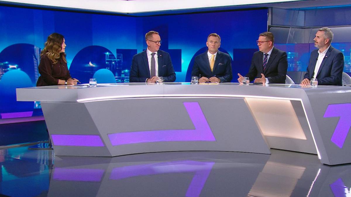 Pięć osób siedzi przy białym stole w studiu telewizyjnym. Cztery osoby to mężczyźni w garniturach, jedna to kobieta w ciemnej bluzce. Wszyscy patrzą przed siebie.