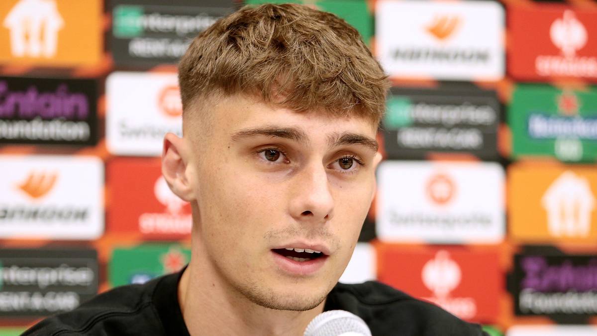 Portret młodego piłkarza o jasnej karnacji, krótkich, kręconych włosach i zarostem.