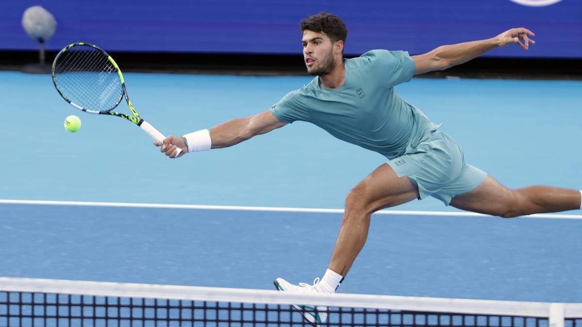 Tenisista w turkusowym stroju odbija piłkę rakietą, w dynamicznym ujęciu podczas meczu.