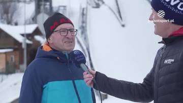 Starszy mężczyzna w okularach i czapce zimowej jest przepytywany przez dziennikarza z mikrofonem. W tle widoczne są zarysy budynk&oacute;w i zaśnieżone otoczenie.