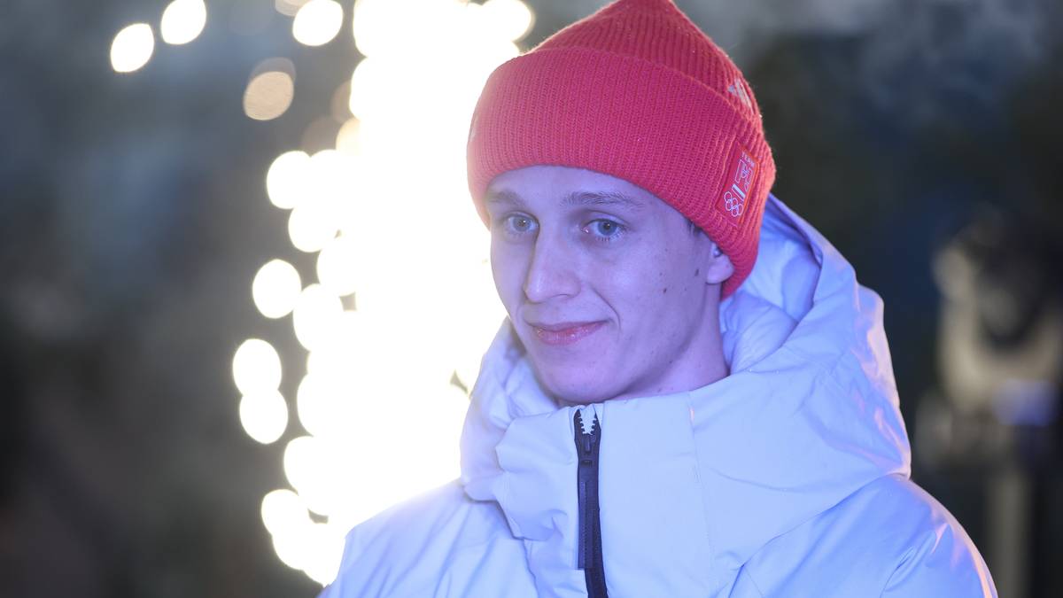 Portret Pawła Wąska w czerwonej czapce i jasnej kurtce, z rozmazanymi światłami w tle.