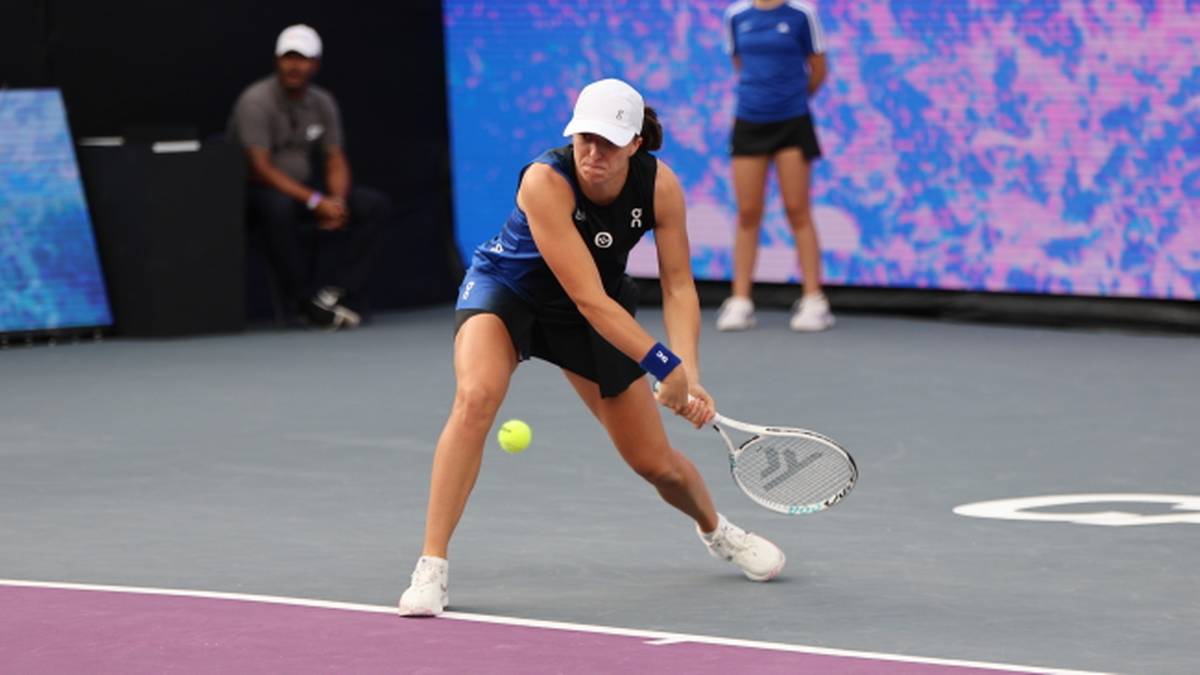 Iga Świątek uderza piłkę rakietą tenisową na korcie.