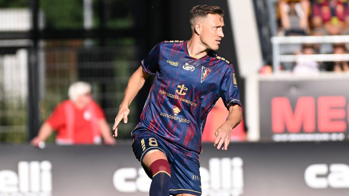 Piłkarz w niebieskiej koszulce z czerwonymi pasami i numerem 18, podczas meczu.