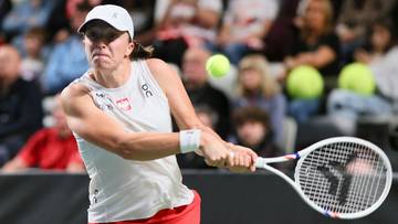 Tenisistka Iga Świątek podczas meczu, skupiona na odbiciu piłki.