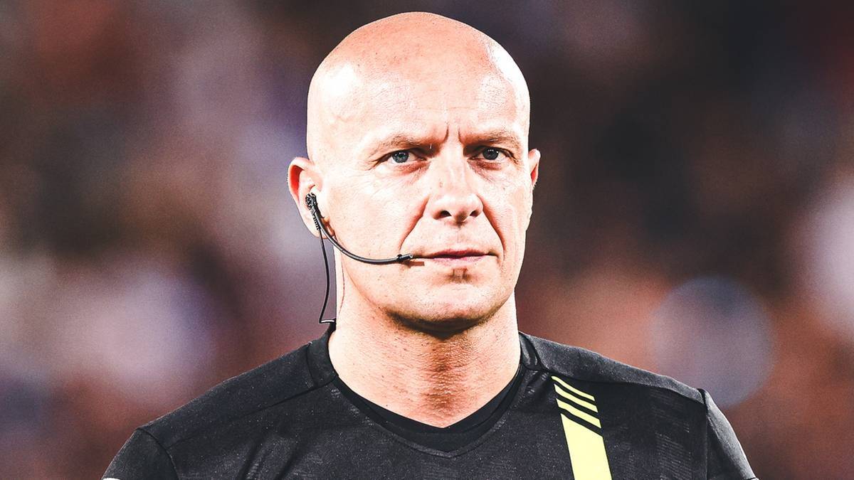 Zbliżenie na łysą głowę mężczyzny w czarnej koszulce sędziego sportowego, noszącego słuchawkę z mikrofonem przy uchu.