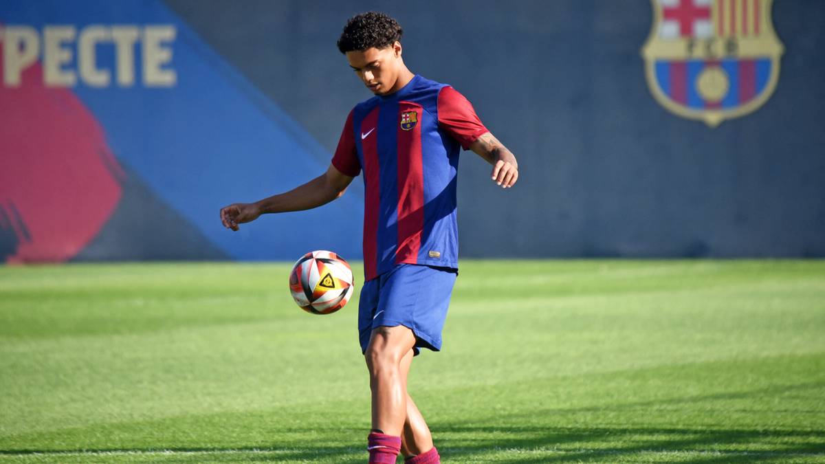 Młody piłkarz w stroju FC Barcelony ćwiczy z piłką na boisku.