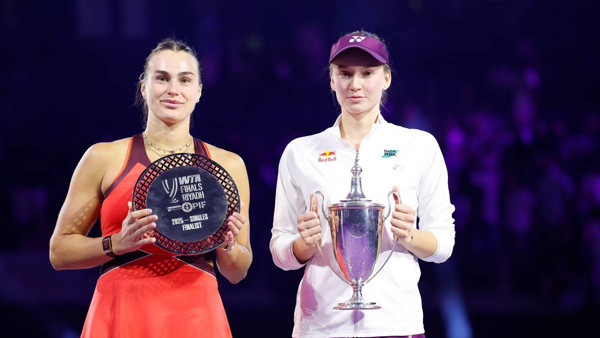 Dwie tenisistki stoją obok siebie, trzymając trofea. Po lewej stronie Aryna Sabalenka w czerwonej sukience trzyma okrągłą nagrodę. Po prawej stronie Jessica Pegula w białej koszulce i czapce trzyma puchar.