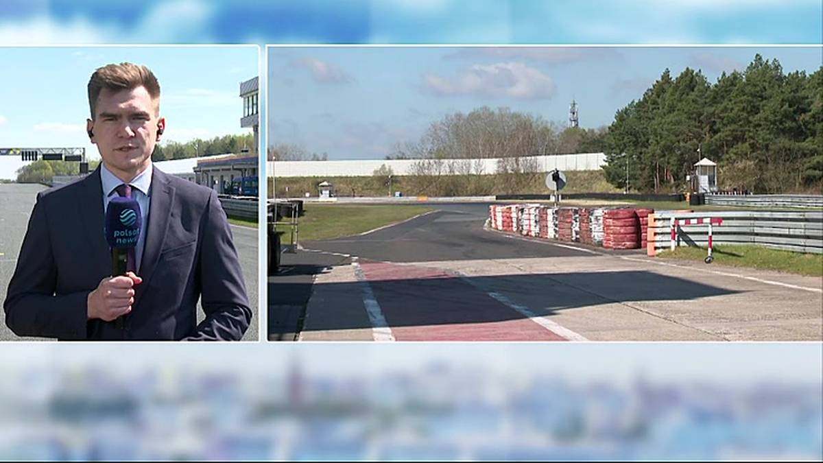 Mężczyzna w garniturze trzyma mikrofon i m&oacute;wi, obok widok pustego toru wyścigowego z barierkami.