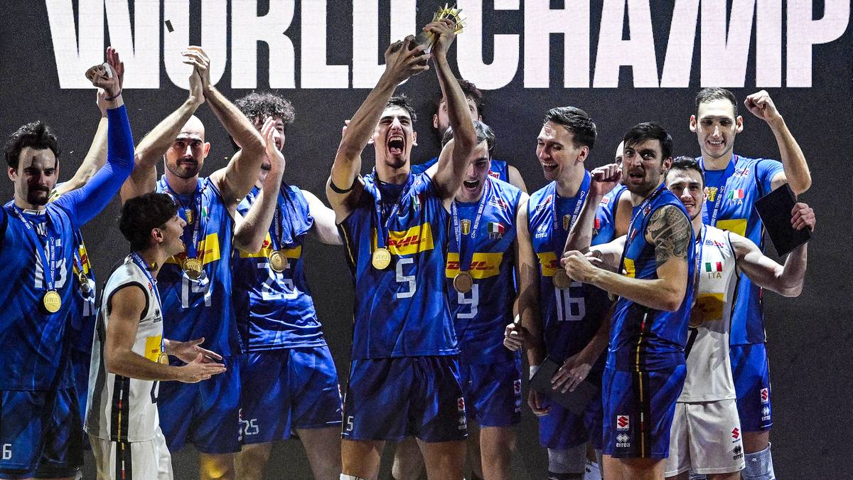 Grupa siatkarzy w niebieskich strojach świętuje zdobycie pucharu, mając na szyjach złote medale. W tle widoczny napis "WORLD CHAMPIONSHIP".