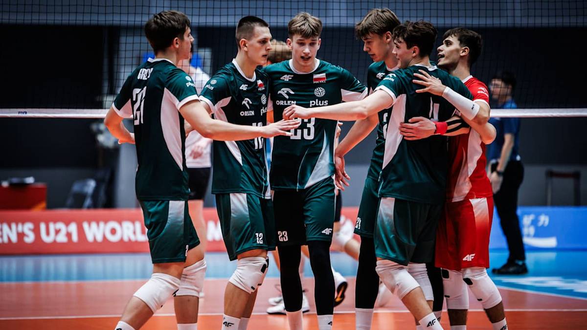 Grupa młodych mężczyzn w ciemnozielonych strojach siatkarskich przytula się na boisku. Jeden z nich trzymając ręce na ramionach innych, patrzy w stronę obiektywu.