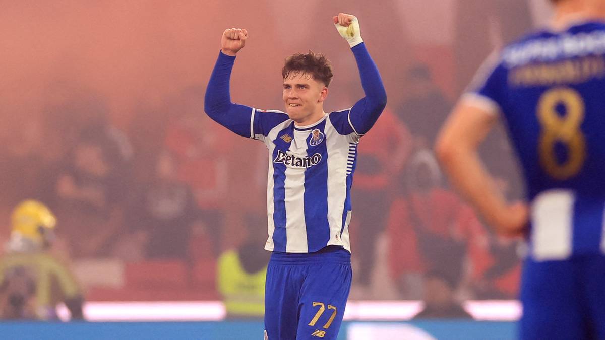 Piłkarze FC Porto na boisku podczas meczu, jeden z nich unosi ręce w geście radości, w tle pirotechnika.