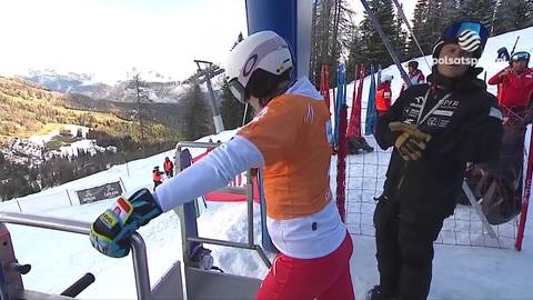 Aleksandra Kr&oacute;l-Walas w stroju narciarskim, z białą kaskiem i pomarańczową bluzką, przygotowuje się do zjazdu na stoku.