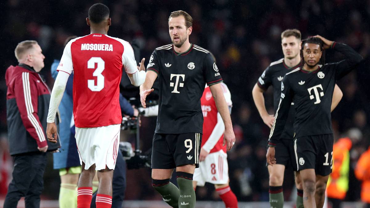 Dwóch piłkarzy w strojach meczowych, jeden w czerwonym z numerem 3, drugi w czarnym z numerem 9, rozmawiają na boisku piłkarskim.