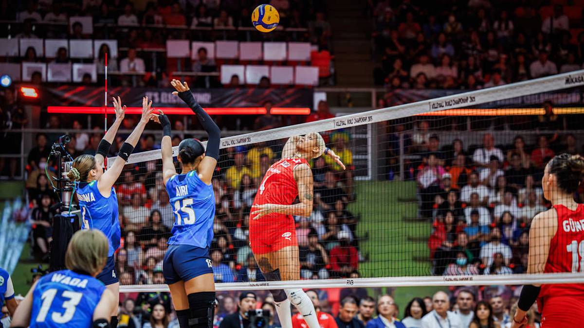 Siatkarki w akcji podczas meczu, piłka w powietrzu, widownia na trybunach.