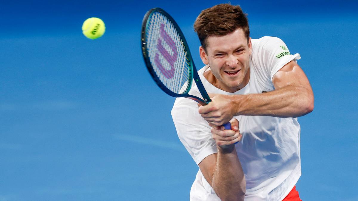 Tenisista odbija piłkę rakietą.