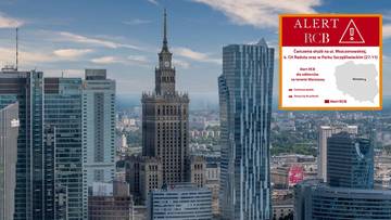 Widok na warszawską panoramę miasta z Pałacem Kultury i Nauki, z nałożonym na prawą stronę komunikatem Alertu RCB.