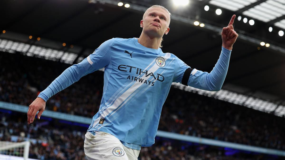 Erling Haaland w jasnoniebieskiej koszulce Manchesteru City celebruje strzelonego gola, wskazując palcem w górę.