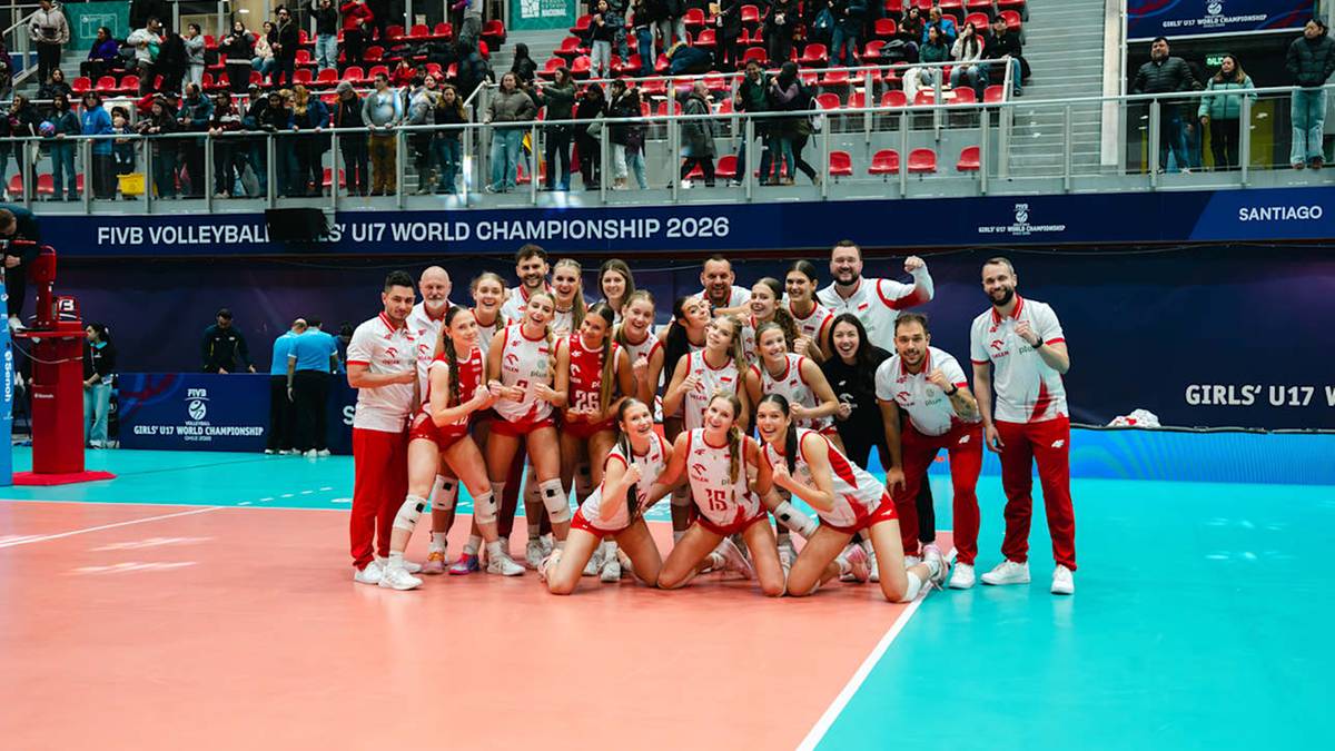 Siatkarki w strojach sportowych pozują do wsp&oacute;lnego zdjęcia na boisku.