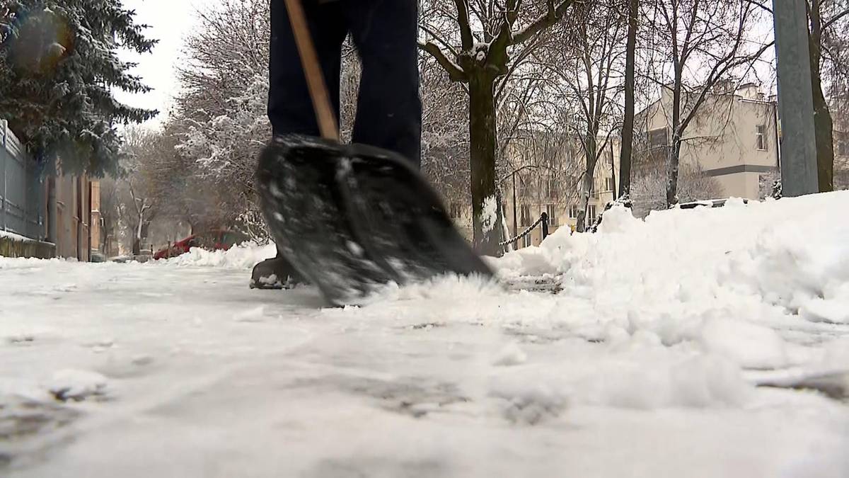 Osoba odśnieża chodnik łopatą.