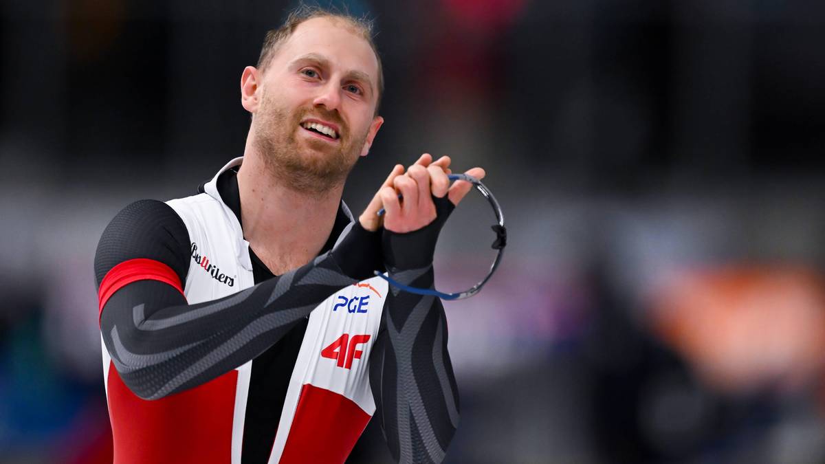 Łyżwiarz szybki w stroju sportowym z okularami w dłoni