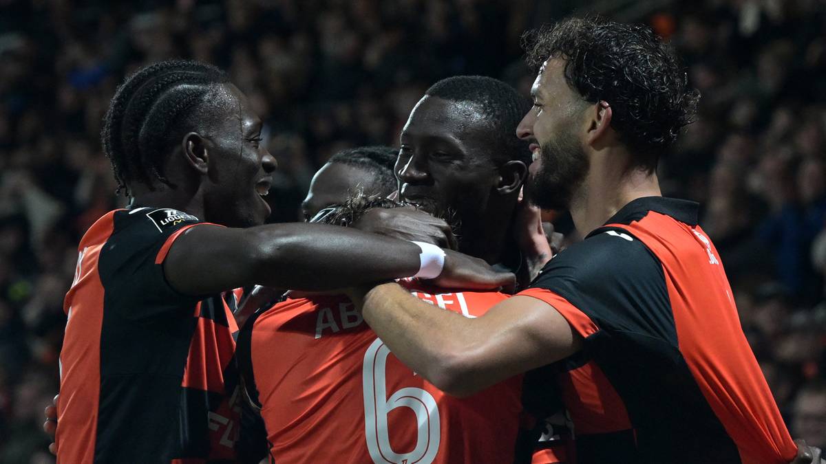 Trzech piłkarzy w pomarańczowych koszulkach obejmuje się po zdobyciu bramki.