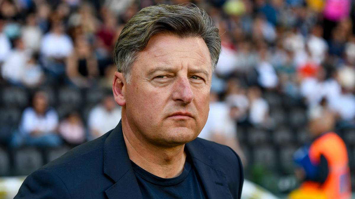 Portret mężczyzny, trenera piłkarskiego, na tle trybun stadionu.