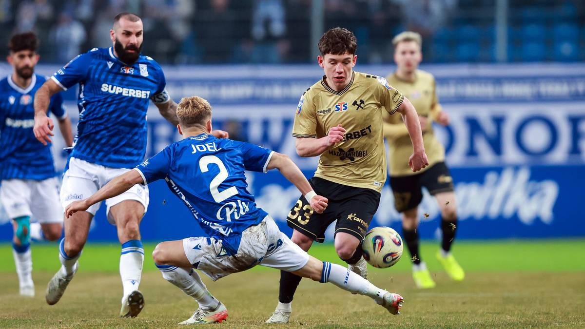 Piłkarze podczas meczu walczą o piłkę na boisku