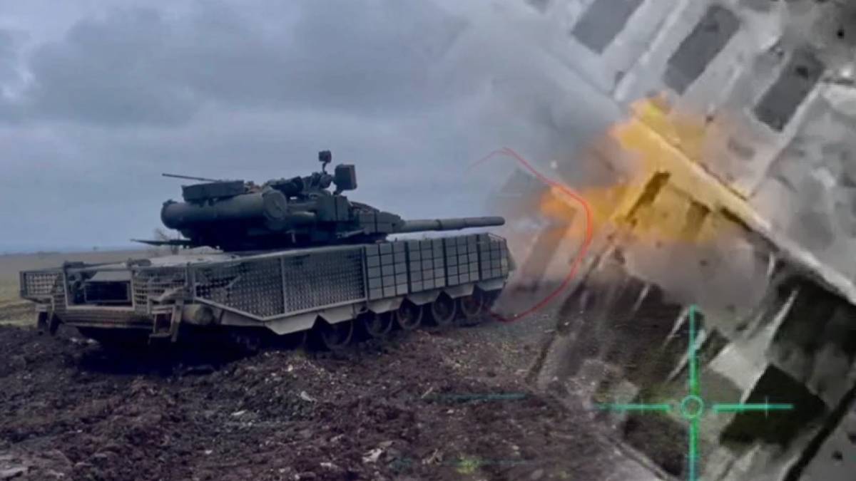 Czołg na polu bitwy z dymem w tle, obok fragmenty zniszczonego budynku, z elementami celownika wskazującymi na atak dronem.