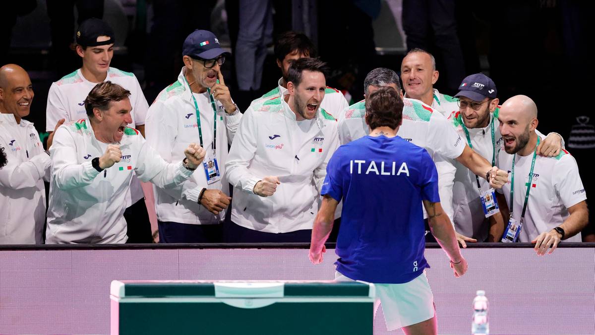 Drużyna tenisowa Włoch świętuje zwycięstwo w meczu, gracze w koszulkach z napisem "ITALIA" cieszą się z awansu do finału.