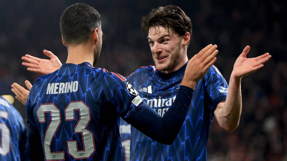 Dwóch piłkarzy w niebieskich strojach świętuje na boisku piłkarskim.