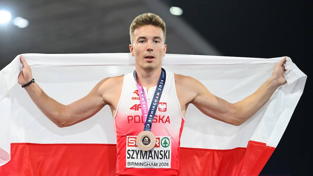 Zawodnik trzyma polską flagę i medal.