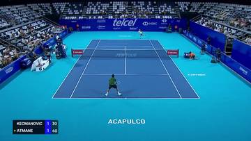 Mecz tenisa ziemnego pomiędzy Miomirem Kecmanovicem a Terence Atmanem na niebieskim korcie z widownią na trybunach. W lewym dolnym rogu wyświetlany jest wynik meczu.