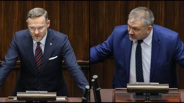 Dwaj mężczyźni w garniturach przemawiający za m&oacute;wnicą w sali sejmowej.