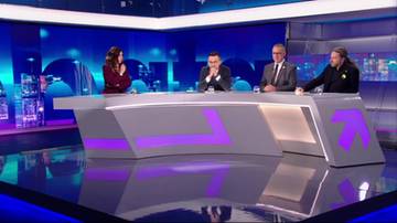 Cztery osoby, w tym dw&oacute;ch mężczyzn i dwie kobiety, siedzą przy nowoczesnym, szarym stole z fioletowymi akcentami w studiu telewizyjnym. W tle widać niebieskie światła i ekrany.