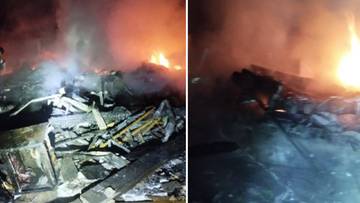 Ruiny płonącego budynku mieszkalnego po rosyjskim ataku w Wilniańsku, widoczni strażacy.