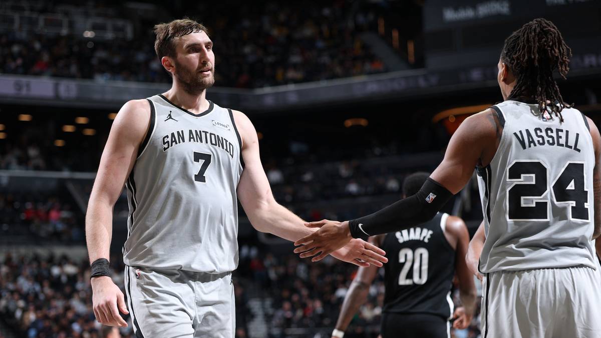Dwóch koszykarzy San Antonio Spurs podaje sobie ręce na boisku podczas meczu.