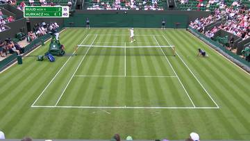 Kort tenisowy na Wimbledonie z zawodniczką w białym stroju w akcji. Na tablicy wynik&oacute;w widnieje nazwisko Hurkacz.