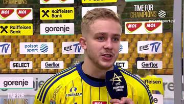 Piotr Jędraszczyk udzielający wywiadu w żółtym stroju sportowym na tle ścianki sponsorów.