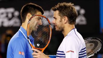 Dw&oacute;ch tenisist&oacute;w podaje sobie ręce na siatce, jeden z nich trzyma rakietę.