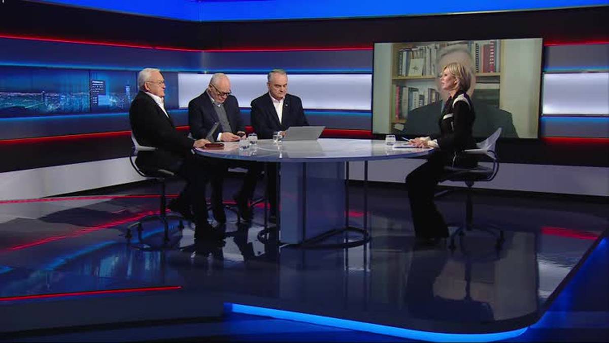 Czterech mężczyzn i jedna kobieta siedzą przy okrągłym stole w studiu telewizyjnym. Na ekranie za nimi wyświetlany jest obraz przedstawiający p&oacute;łkę z książkami.