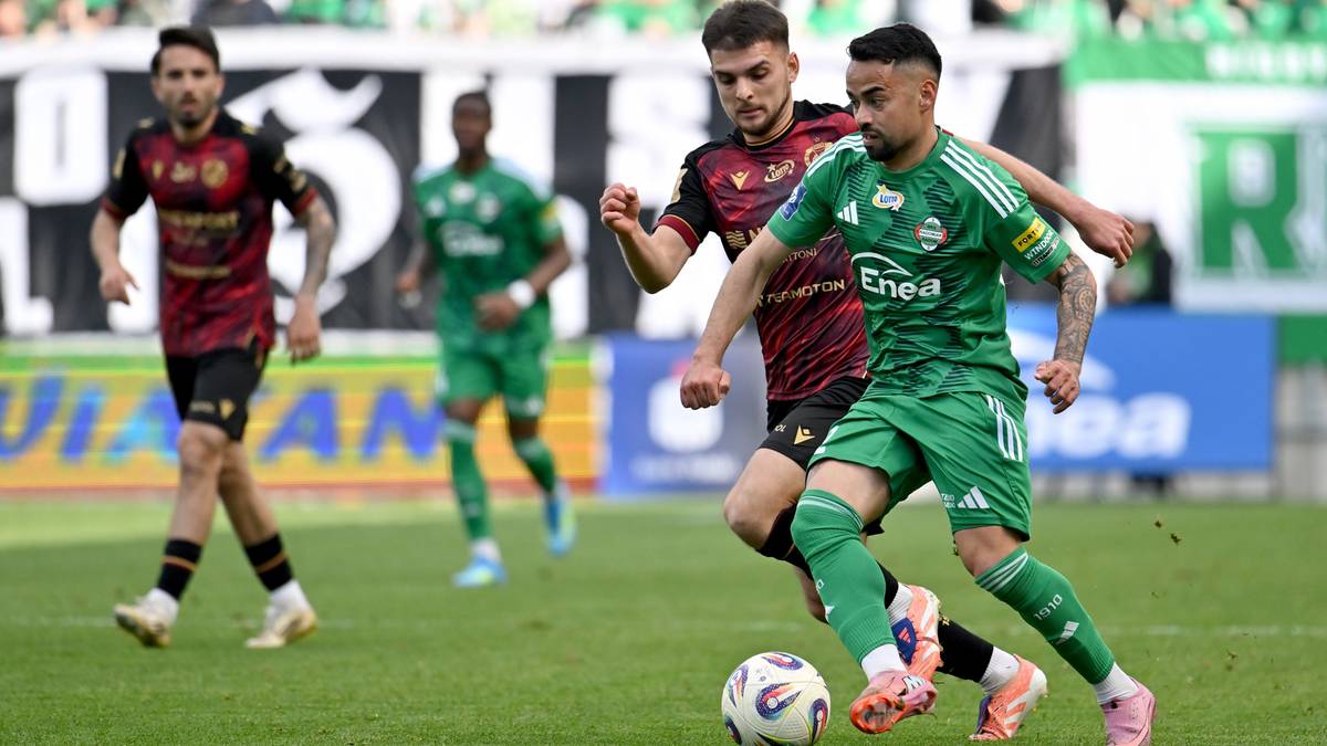 Piłkarz w zielonym stroju z numerem 10 na plecach prowadzi piłkę, pr&oacute;bując ominąć przeciwnika w bordowym stroju.