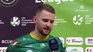 Mężczyzna w zielonej koszulce z ż&oacute;łtym kołnierzykiem, trzyma mikrofon Polsatsport.pl przed twarzą.