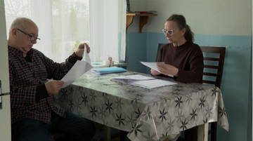 Emerytka Elżbieta R&oacute;żnicka i emeryt Adam R&oacute;żnicki siedzą przy stole i przeglądają dokumenty.