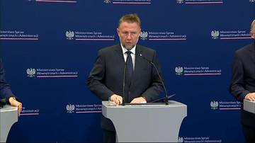 Marcin Kierwiński za m&oacute;wnicą podczas konferencji prasowej na tle ścianki MSWiA.