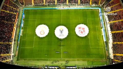 Widok z lotu ptaka na boisko piłkarskie z trzema okręgami reprezentującymi logotypy klub&oacute;w Galatasaray SK i Trabzonspor.